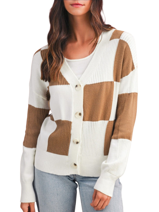 A woman wearing a color-block knit cardigan sweater with white and tan blocks, paired with light blue jeans against a plain white background.