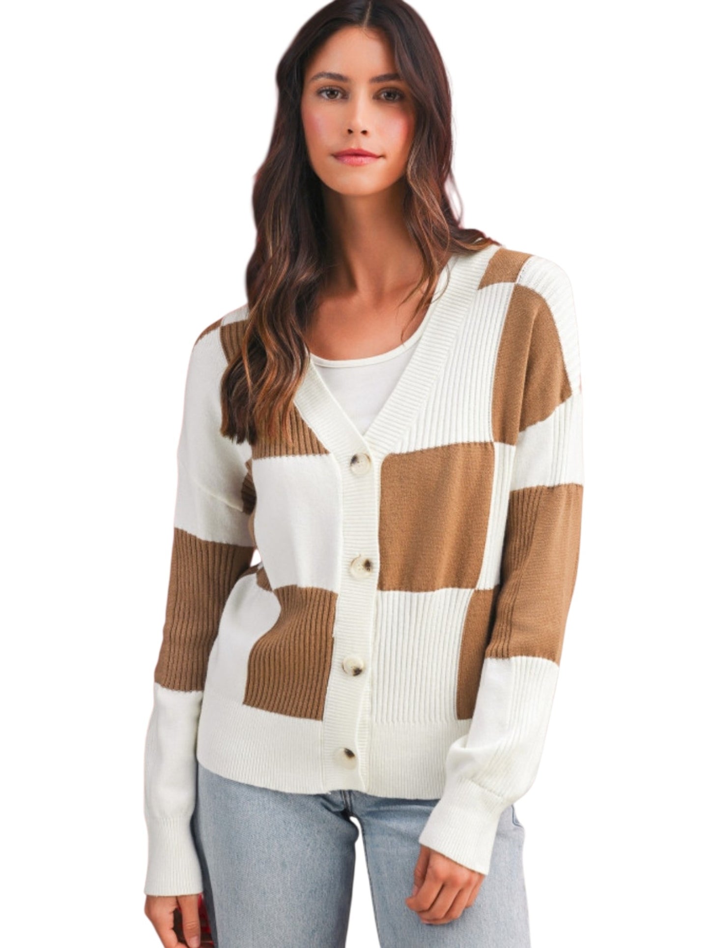 A woman wearing a color-block knit cardigan with cream and tan patches, paired with light blue jeans, against a plain white background.