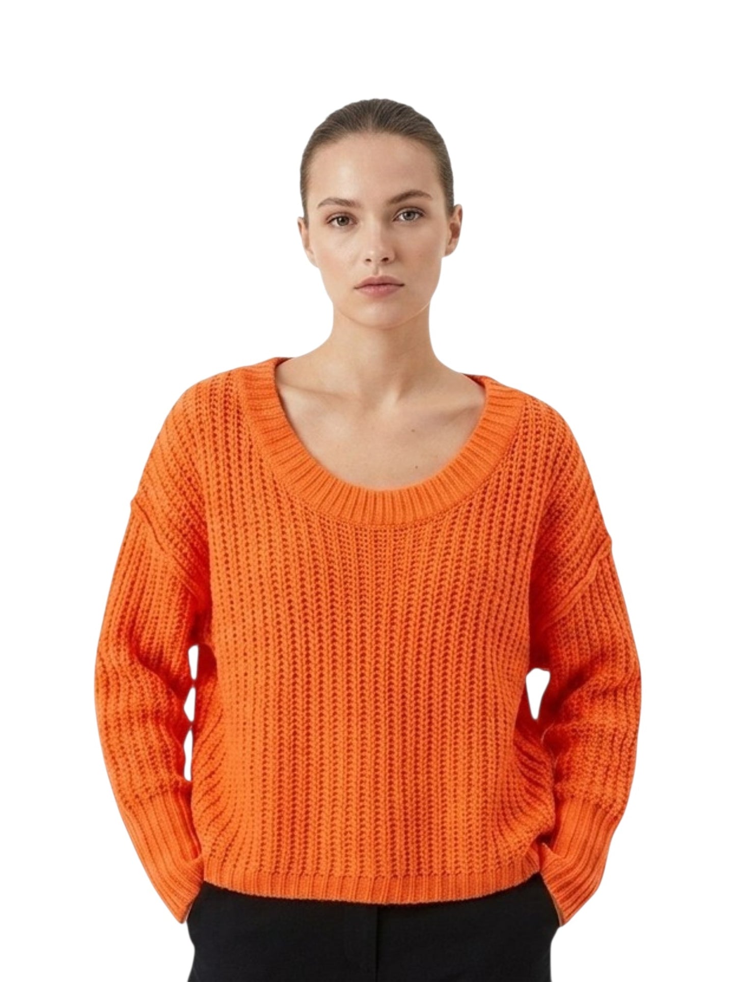 A woman wearing a bright orange chunky knit sweater with a wide scoop neckline, paired with black pants, photographed against a solid white background.