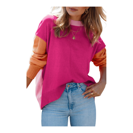 A close-up shot of the oversized magenta sweater, showing the ribbed texture of the cuffs and the light pink collar. The model has her hand tucked into her denim pocket, emphasizing the relaxed, slouchy fit of the knit.