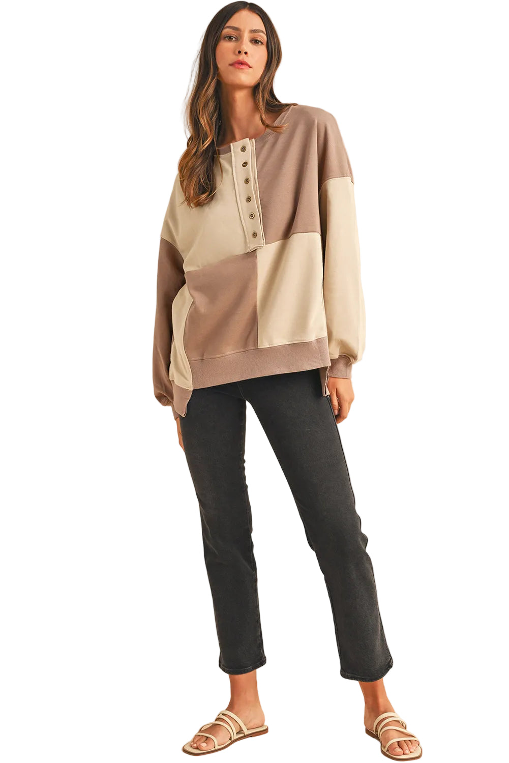 Woman wearing a patchwork sweater and black pants on a white background
