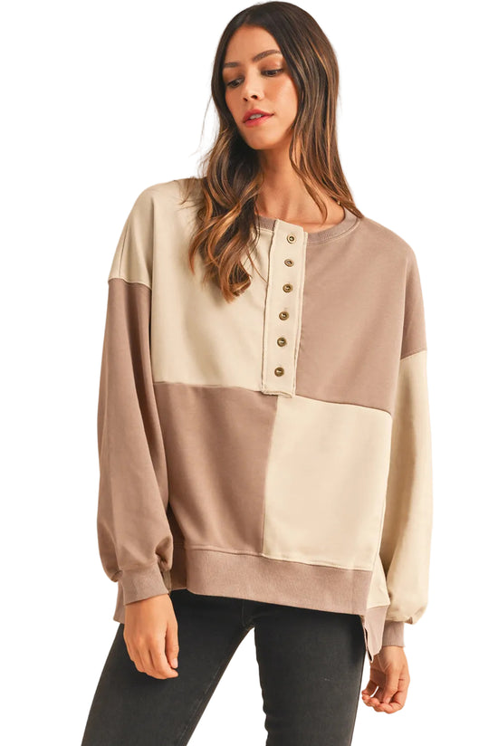 Model styling the cream and taupe neutral version of the patch button sweater, showing the relaxed neck line.