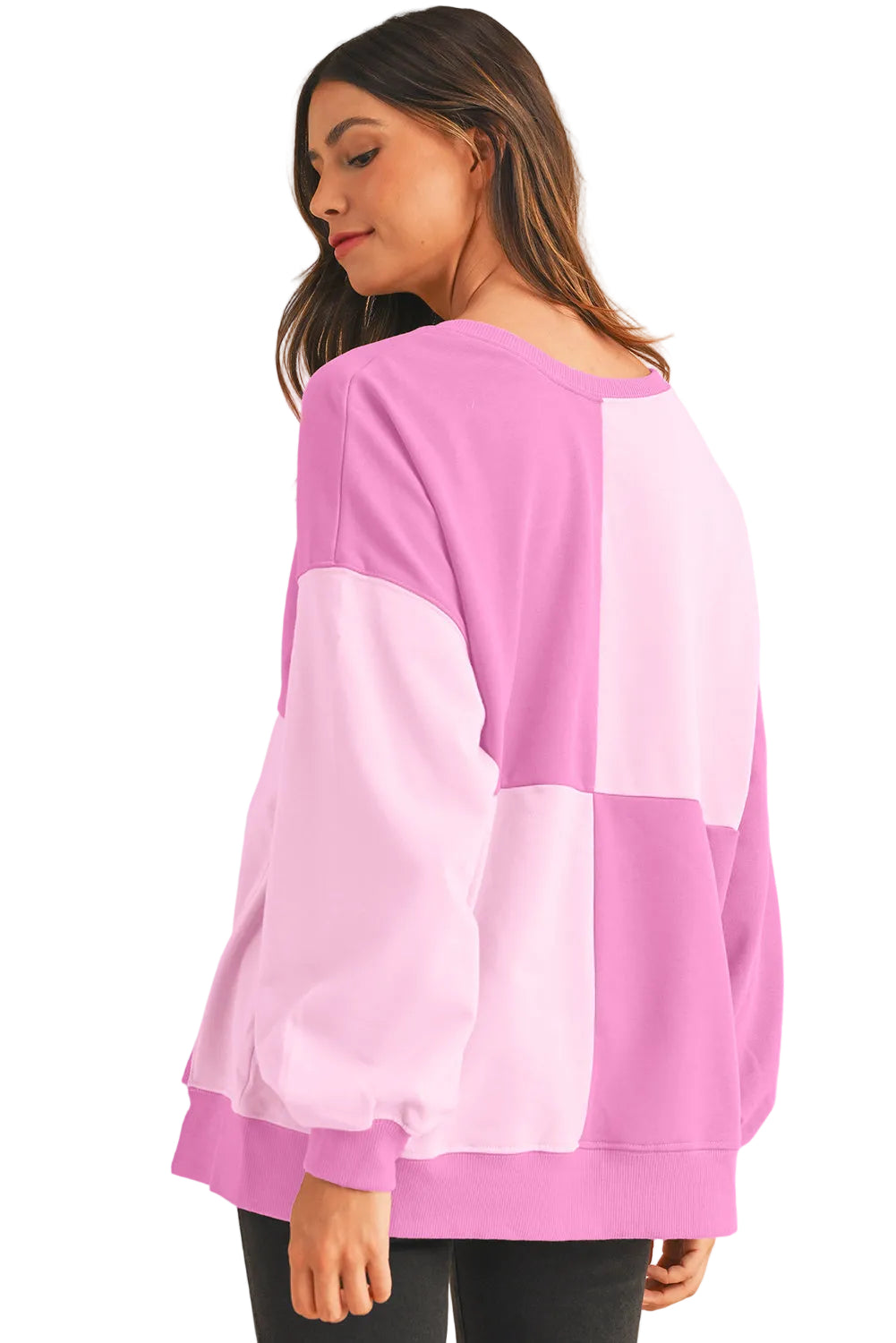 Rear view of the model showcasing the multi-panel colorblock design on the back of the pink sweater.