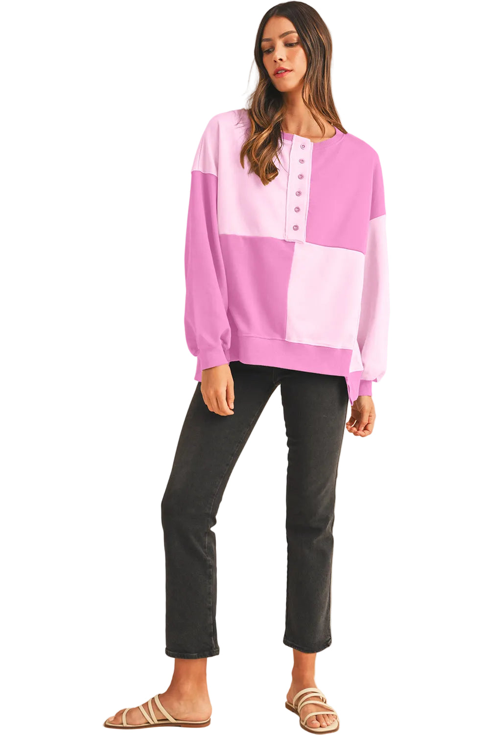 Woman wearing a pink and purple sweater with black pants on a white background