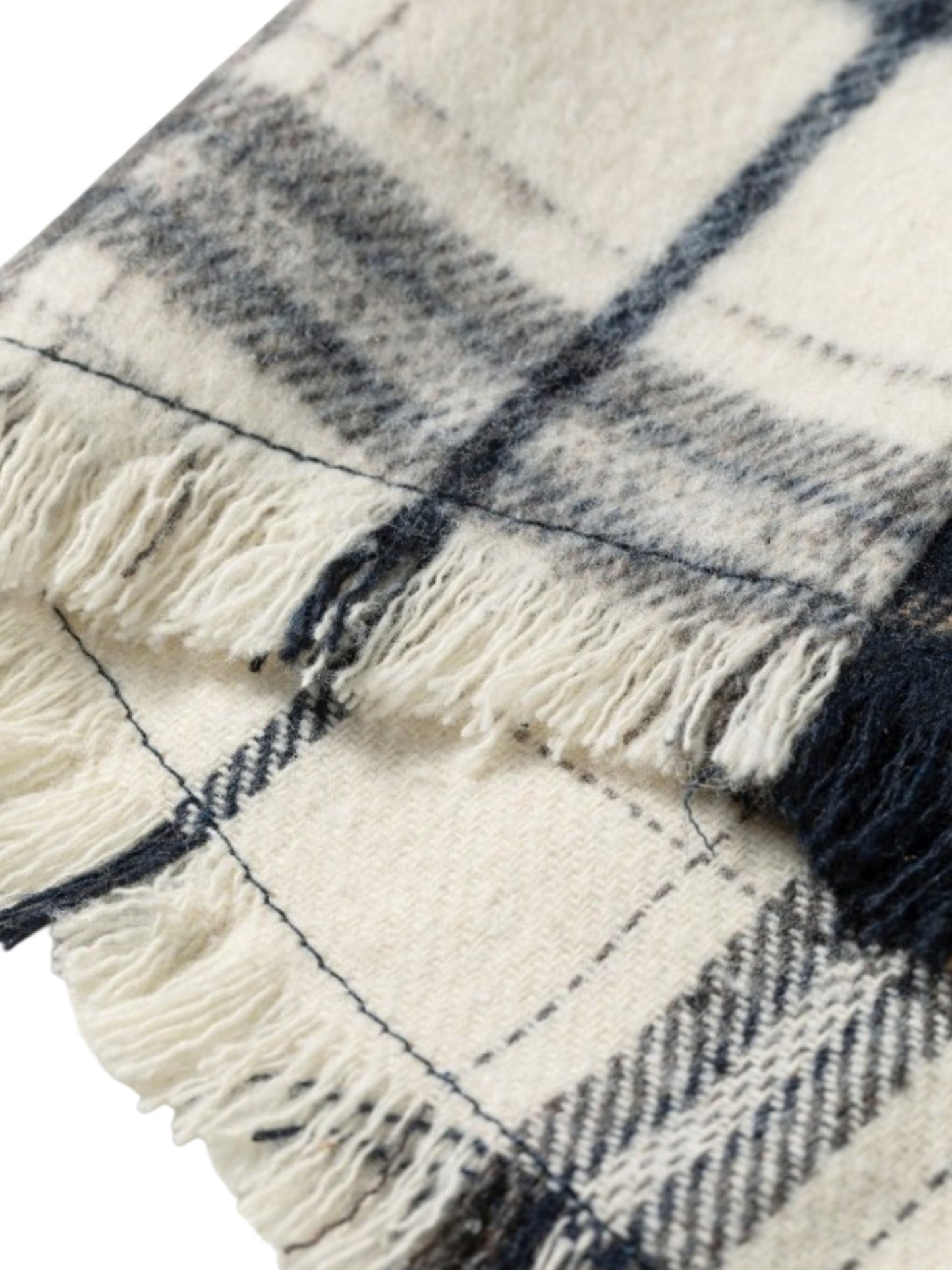 A close-up of a woven plaid blanket or scarf with cream-colored fringed edges and dark navy blue stripes.