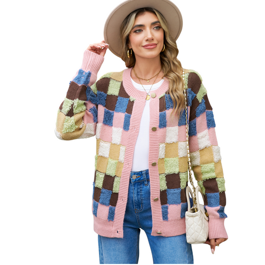 A woman wearing a modern colourblock plaid cardigan featuring textured pink, blue, brown, and olive green squares with gold-toned buttons.