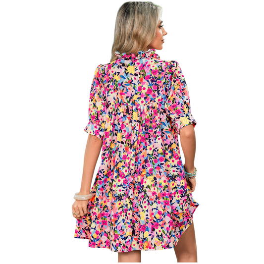 Back view of a woman wearing a lilac floral smocked maxi dress featuring a square neckline, short puff sleeves, and a tiered skirt with an all-over purple botanical print.