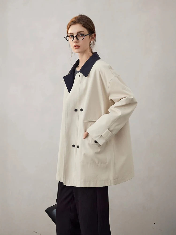 Person wearing a beige coat with black collar and cuffs on a plain background