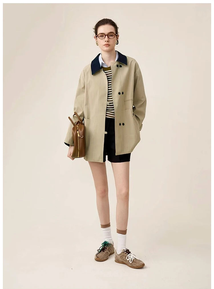 Person wearing a beige trench coat, striped shirt, and shorts on a plain background