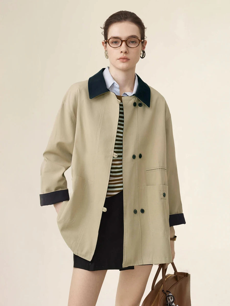 Woman wearing a beige trench coat with black trim on a plain background