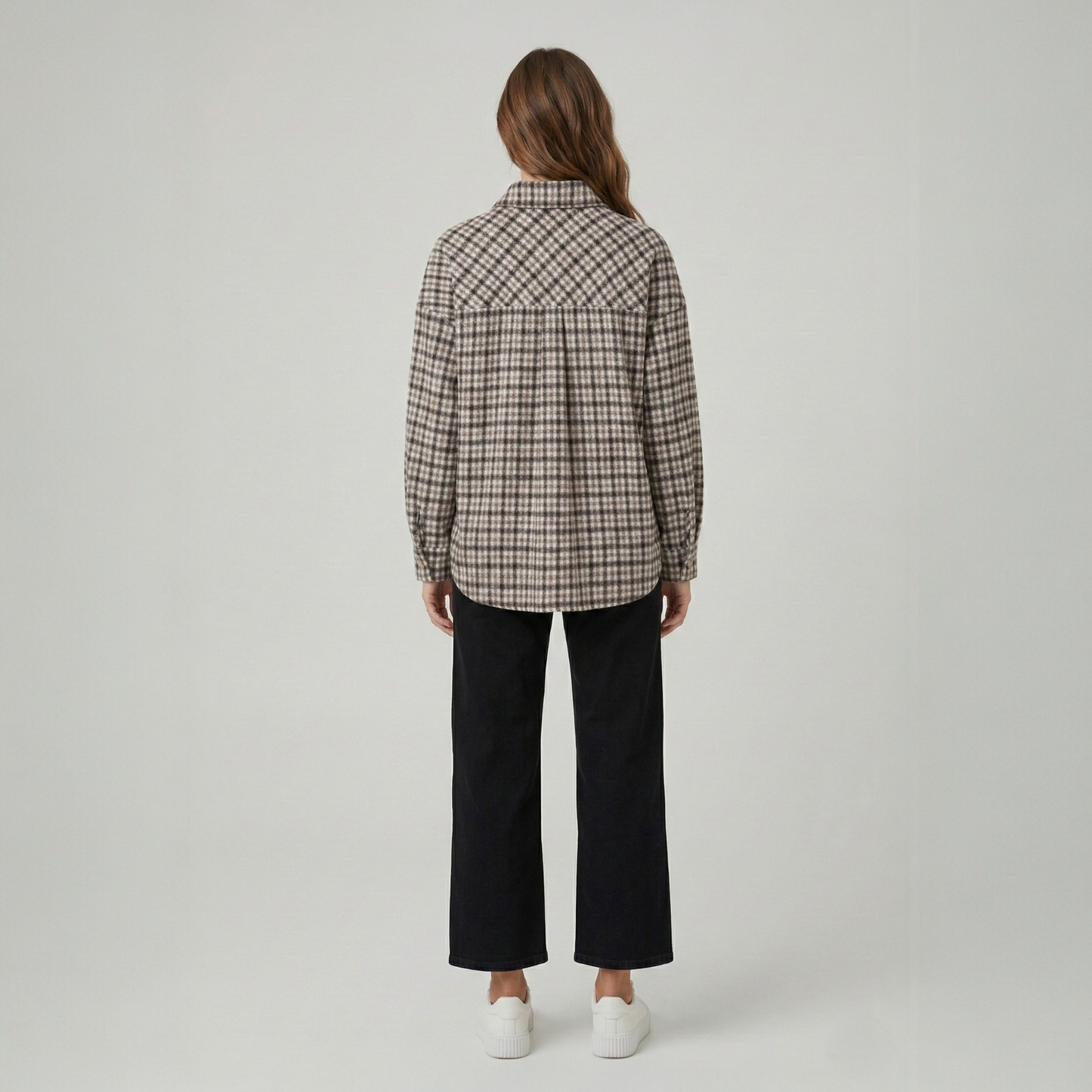 Back view of a model wearing a brown and tan houndstooth and cable-knit patchwork shacket, highlighting the unique panelled design.