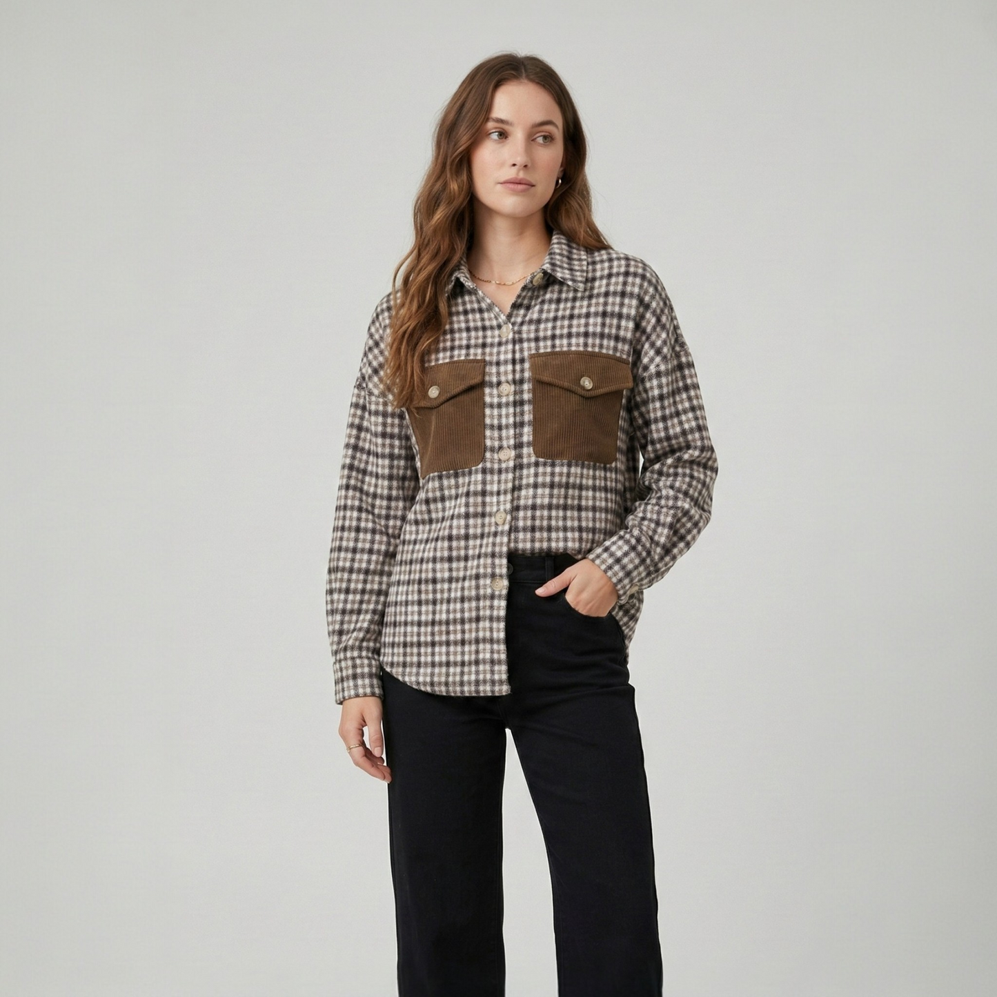 Close-up view of a brown and tan patchwork shacket, featuring button-down detailing, utility pockets, and a mix of houndstooth and cable-knit textures.