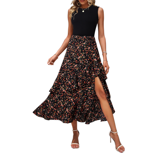 Front view of a woman wearing a contrast maxi dress featuring a black slim-fit tank bodice and a tiered floral ruffled skirt with a high side split in mid-stride to show movement.