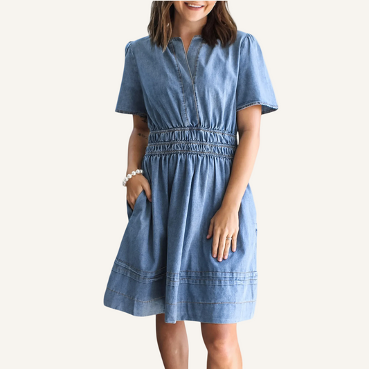 Woman wearing a blue denim dress on a neutral background