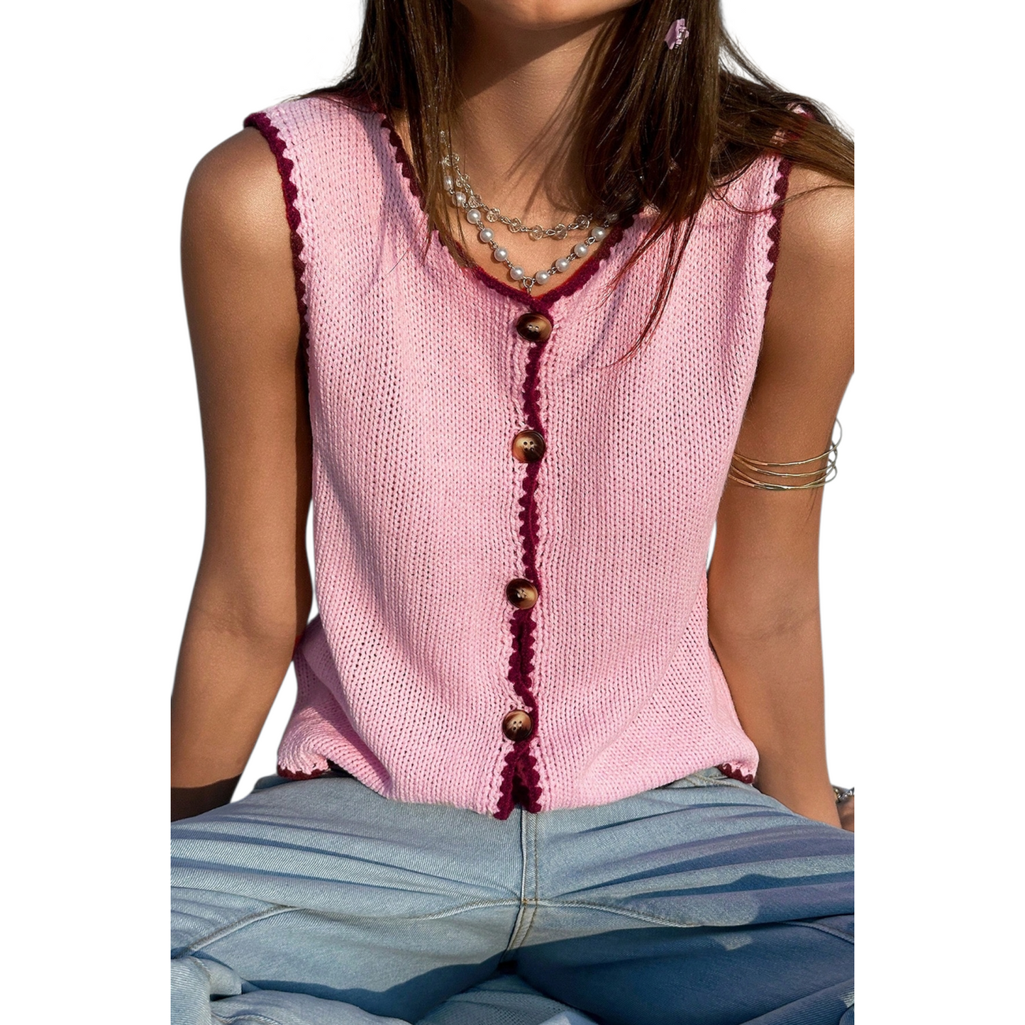 Pink knitted vest with buttons worn by a person on a white background