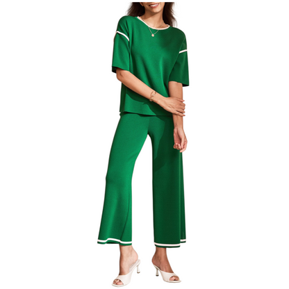 A woman wearing a green two-piece knit loungewear set featuring a half-sleeve top with contrast trim and matching high-waisted wide-leg pants.