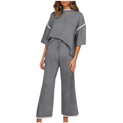 Woman wearing a gray outfit with white trim on a white background