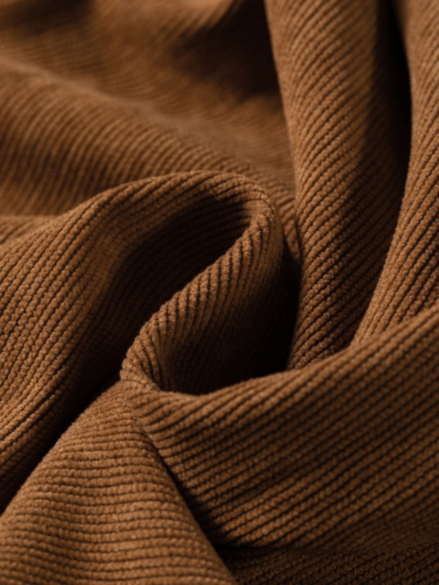 A close-up of draped brown ribbed fabric, showing the texture and folds in detail.