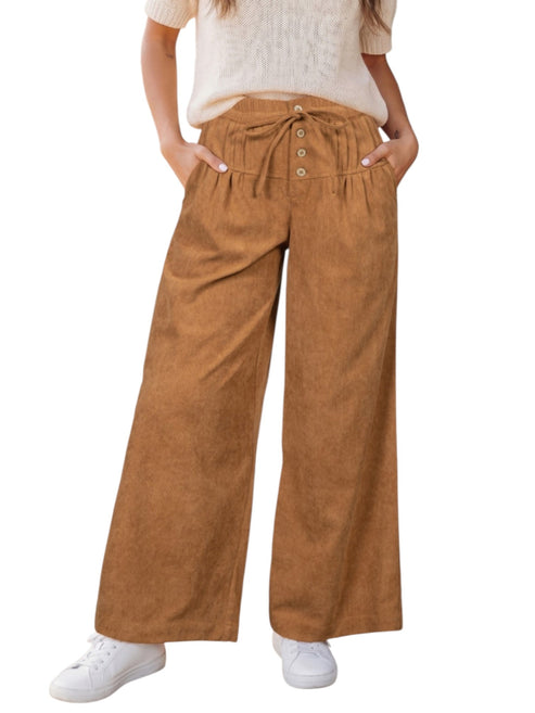 A person wearing high-waisted, wide-leg brown corduroy pants with a drawstring waist and button details, paired with a cream knit top and white sneakers, shown against a plain white background.