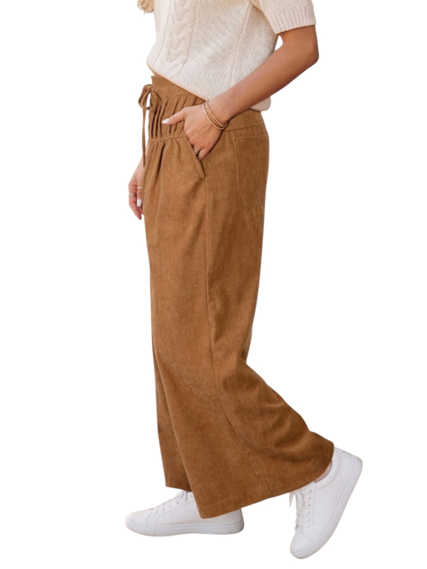 A person wearing high-waisted, wide-leg brown corduroy pants with a drawstring waist, paired with a cream short-sleeve knit top and white sneakers, shown against a plain white background.