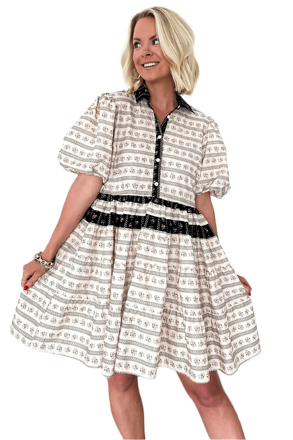 Woman wearing a cream boho mini dress with floral and striped patterns, featuring bubble sleeves and black button accents, styled for a casual and chic look.
