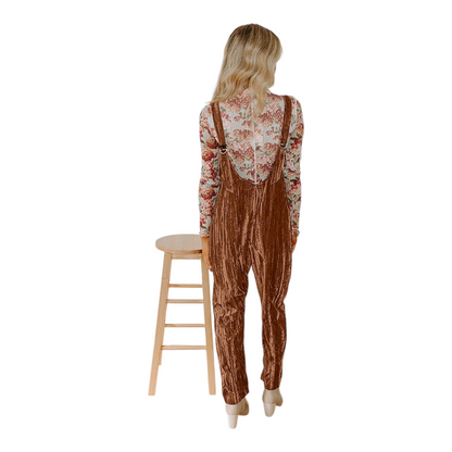 Person wearing brown patterned overalls standing next to a wooden stool on a white background