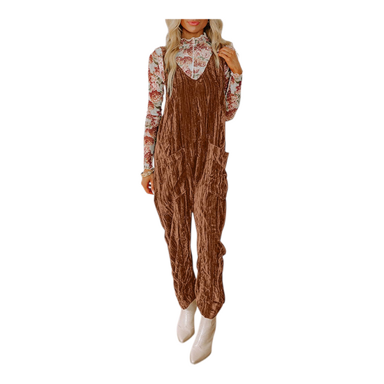 Woman wearing a brown corduroy jumpsuit with a white floral shirt underneath on a white background