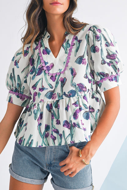 Woman wearing a floral blouse with purple accents and denim shorts on a white background