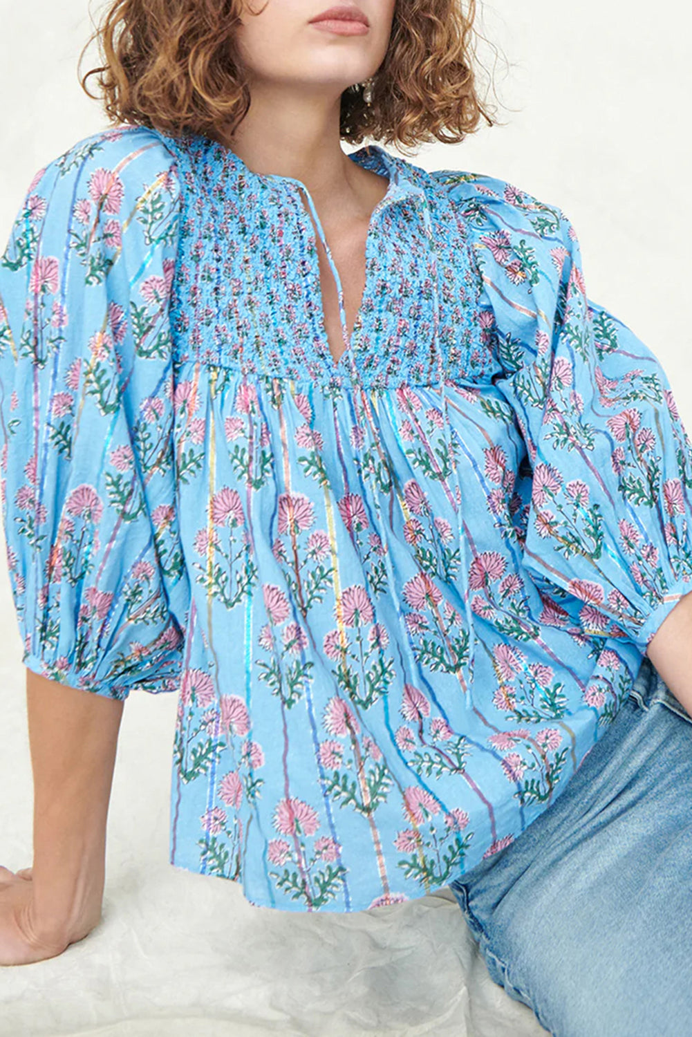 Model sitting in a light blue striped floral blouse with half sleeves.