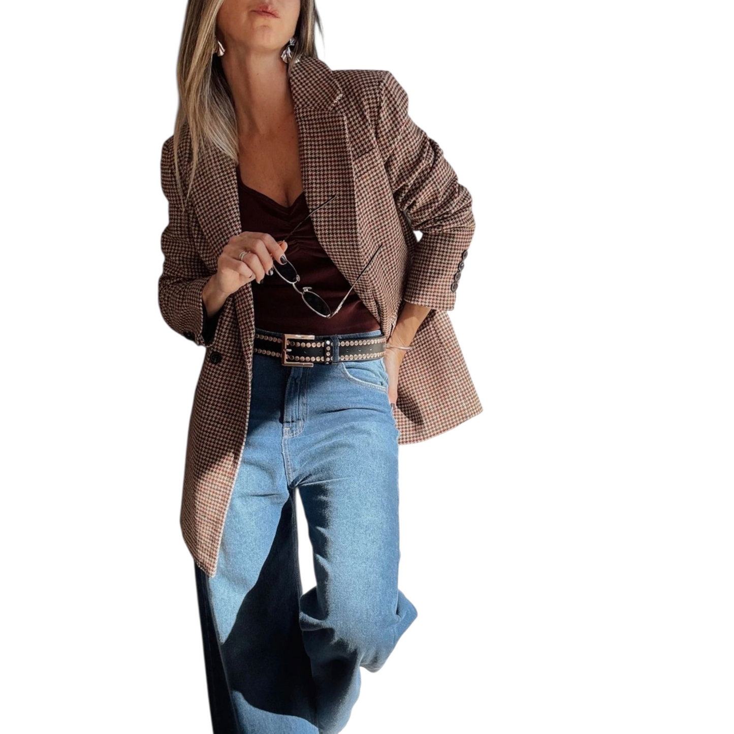 Woman wearing a brown checkered blazer, brown top, and blue jeans on a white background