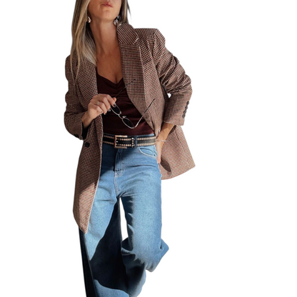 Woman wearing a brown checkered blazer, brown top, and blue jeans on a white background