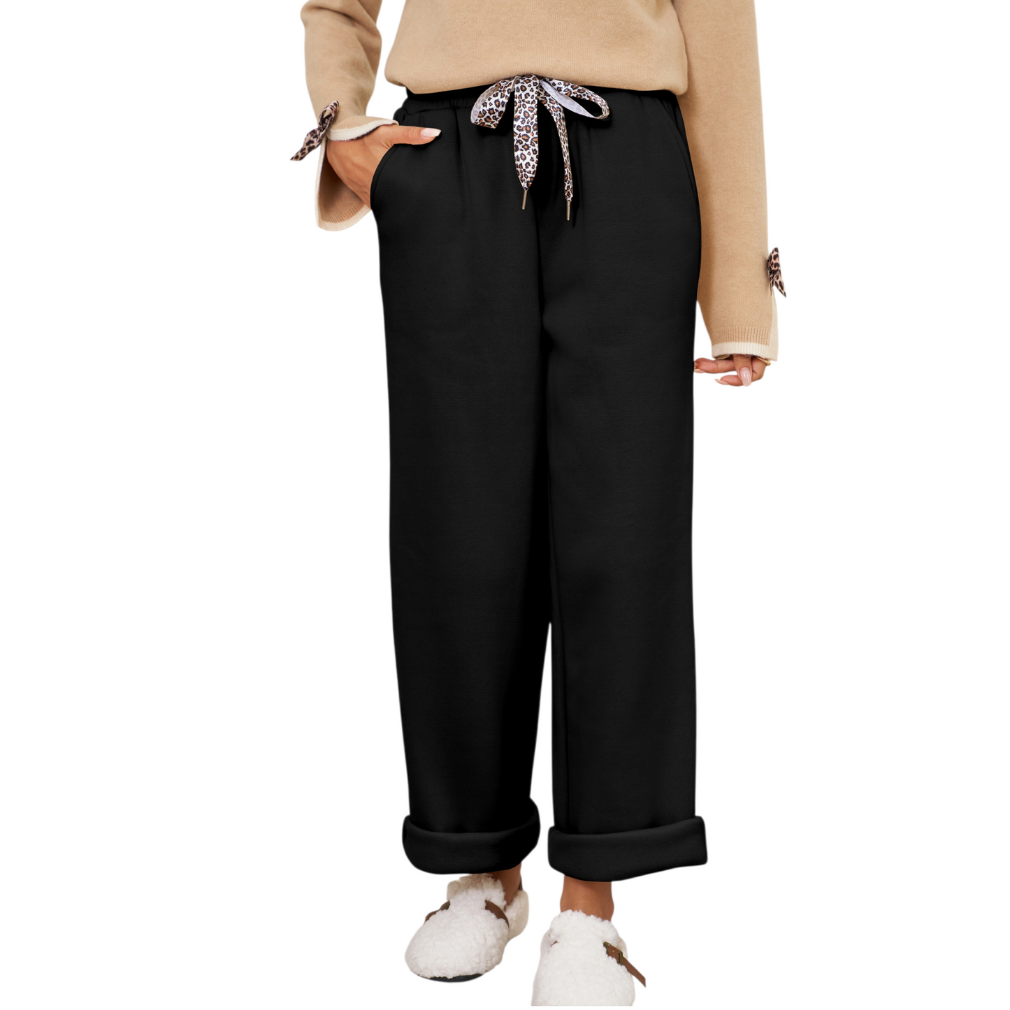 Person wearing black pants with a leopard print ribbon, beige sweater, and white shoes on a white background
