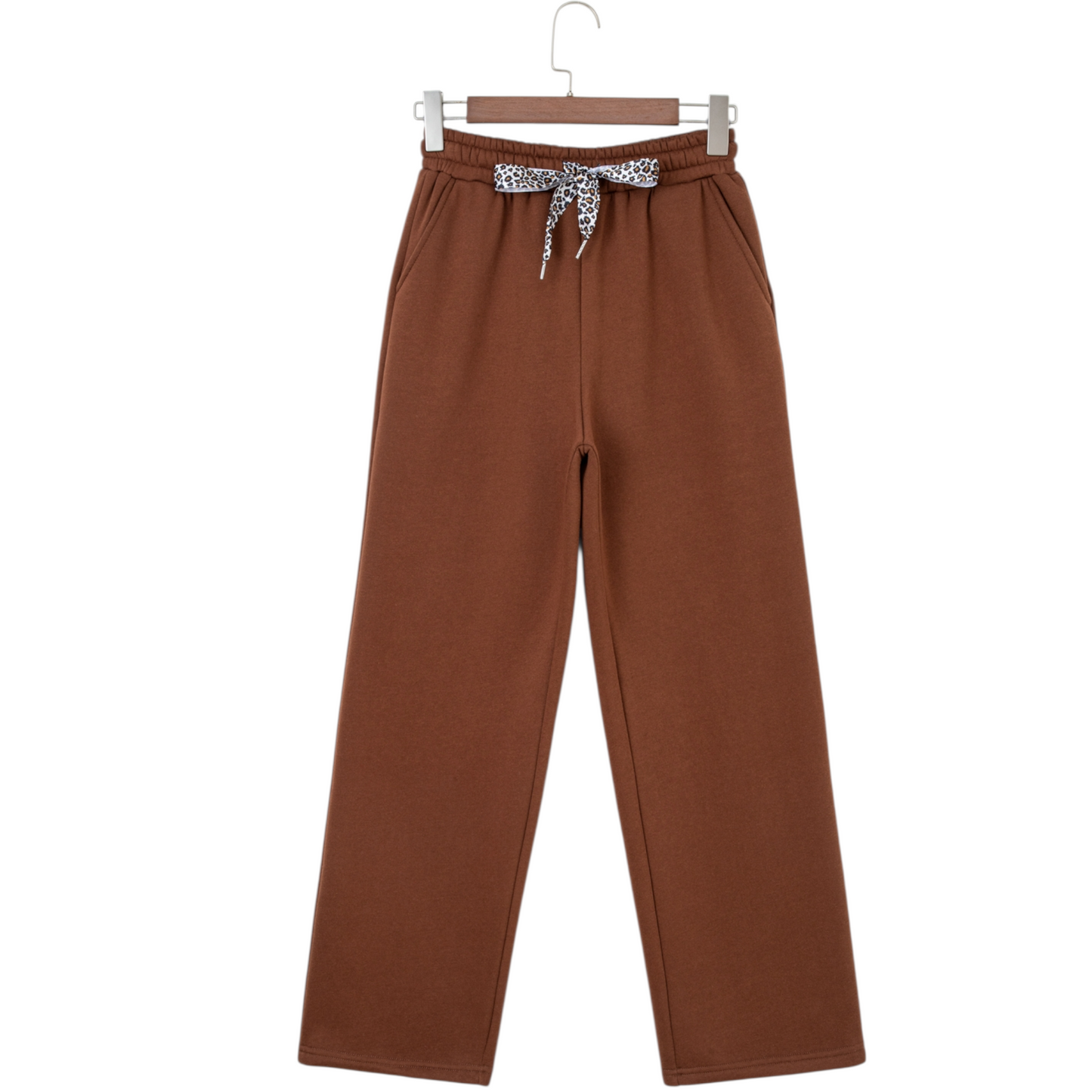 Brown pants with a patterned bow on a hanger against a white background