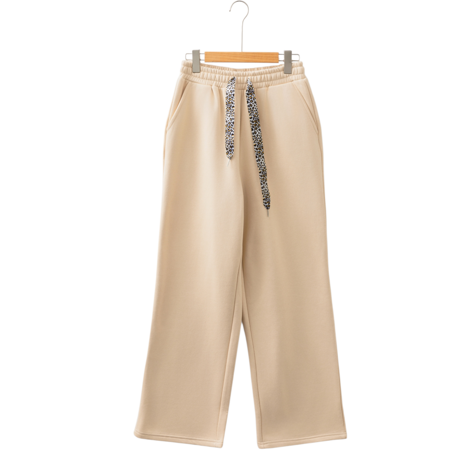 Beige pants with a decorative drawstring on a white background
