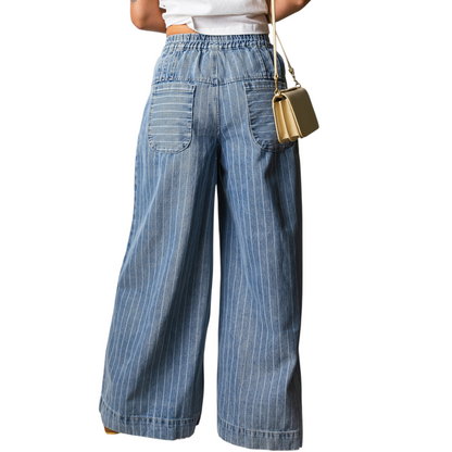 Wide-leg blue jeans worn by a person on a white background