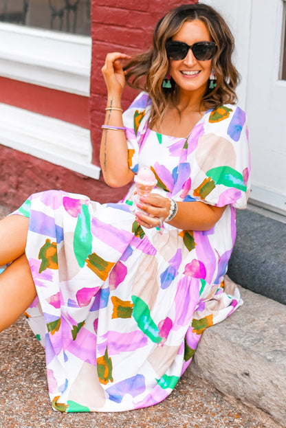 Front view of a sitting model in a purple print dress with bubble short sleeves, holding an ice-cream cone in her left hand on a street setting.