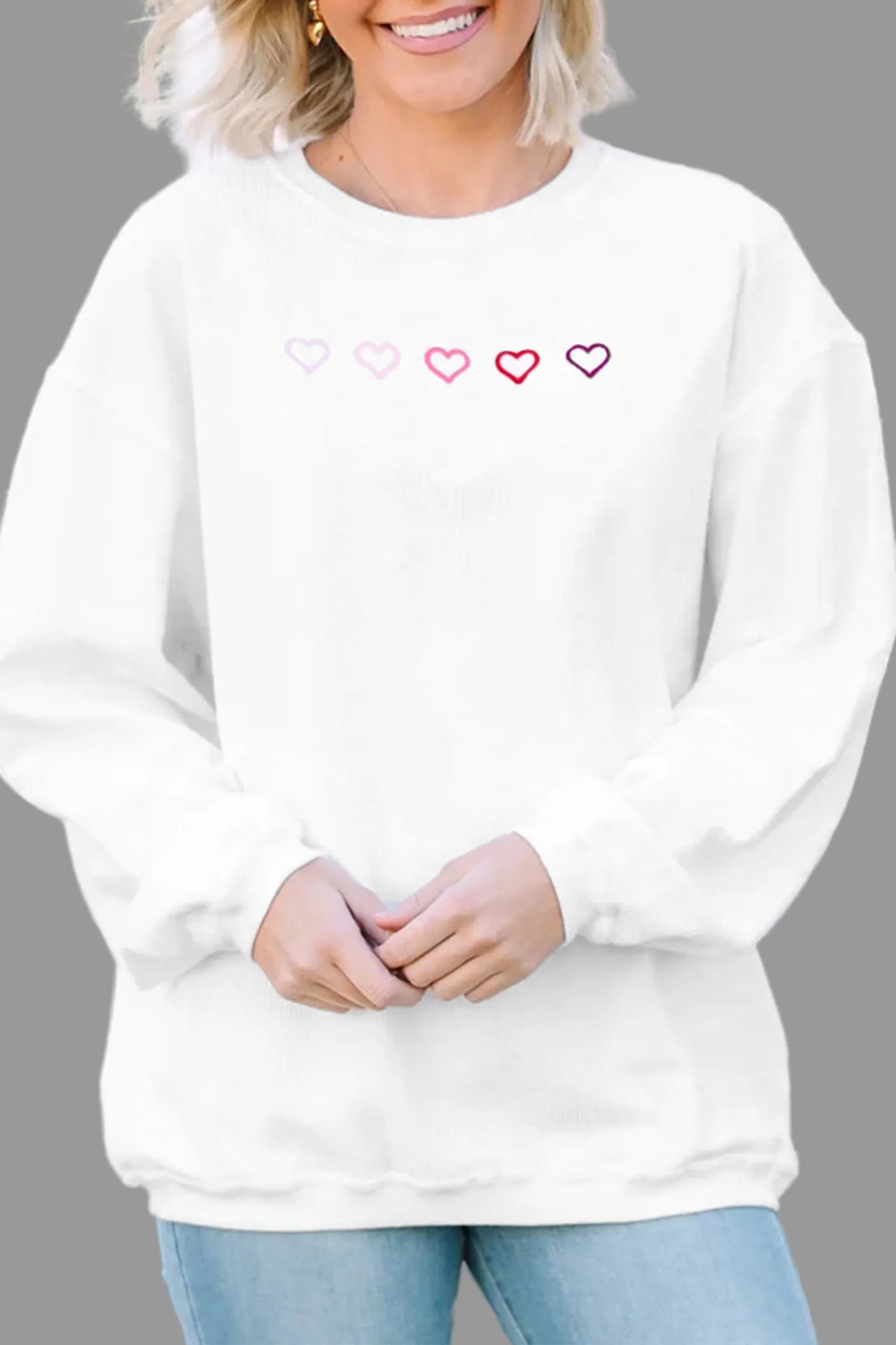 Person wearing a white sweatshirt with heart designs on a blurred outdoor background
