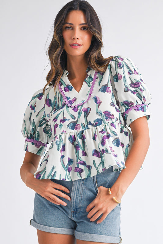 Woman wearing a floral blouse and denim shorts on a white background