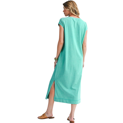 Woman wearing a turquoise dress with a slit on a white background