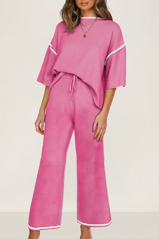 Person wearing a pink outfit with white trim on a plain background