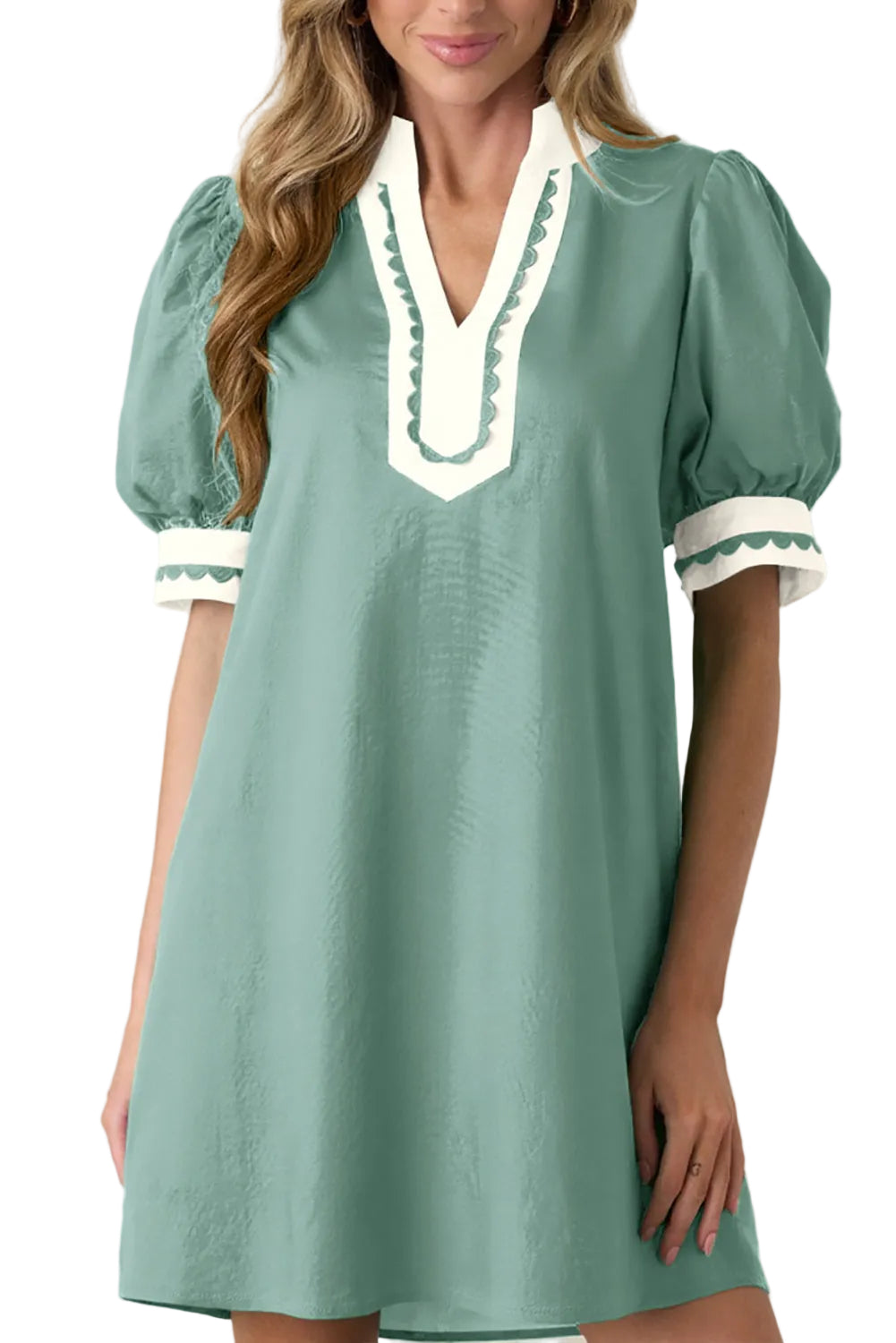 Green dress with white trim worn by a model on a beige background
