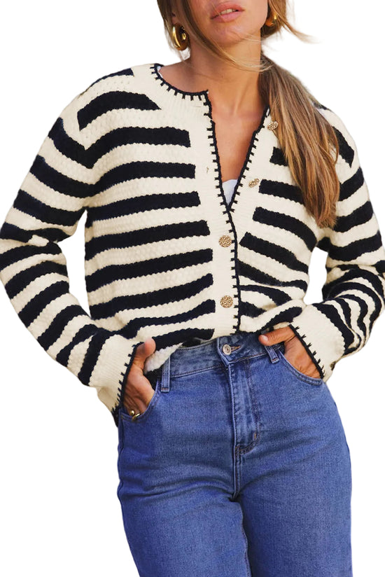 Person wearing a black and white striped cardigan with blue jeans on a white background