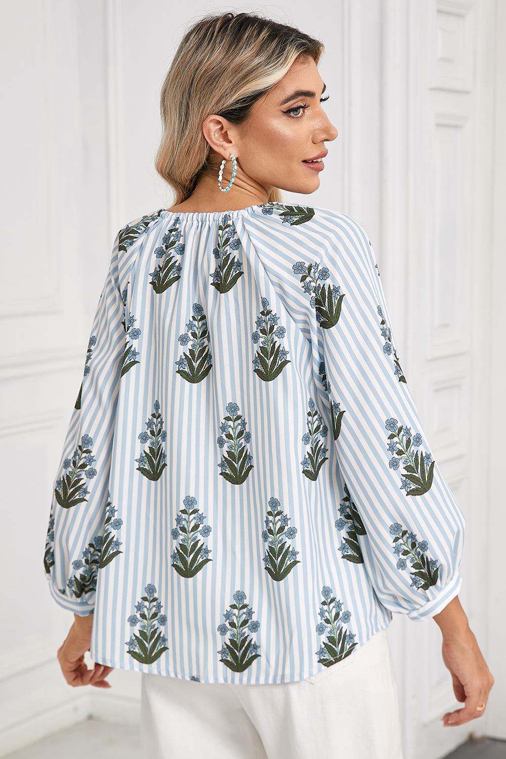 Back view of a blue floral striped blouse with long sleeves, perfect for spring and summer, worn by a model showcasing a boho-chic style.