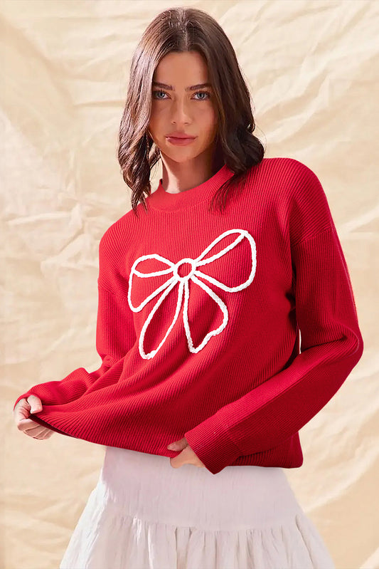 Woman wearing a red sweater with a white bow design on a beige background