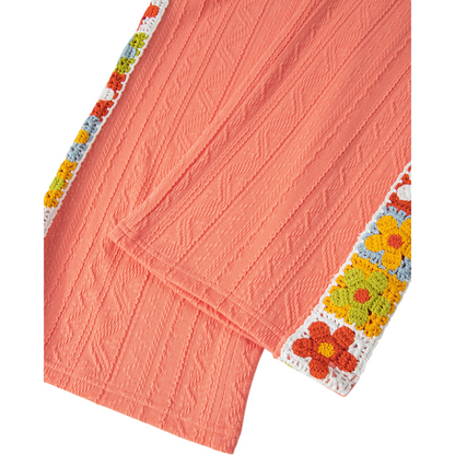 Coral fabric with a colorful floral crochet border on a white background