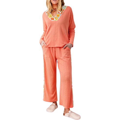 Woman wearing a coral pajama set with a colorful collar on a white background