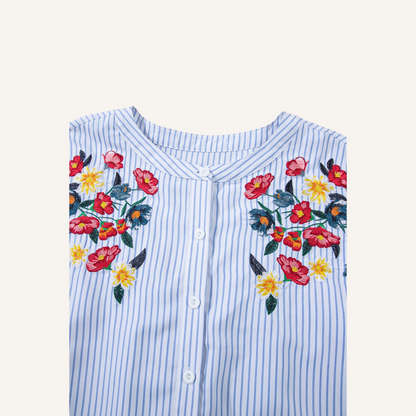 Close-up of intricate red and yellow floral embroidery on a blue pinstripe 100% polyester fabric.