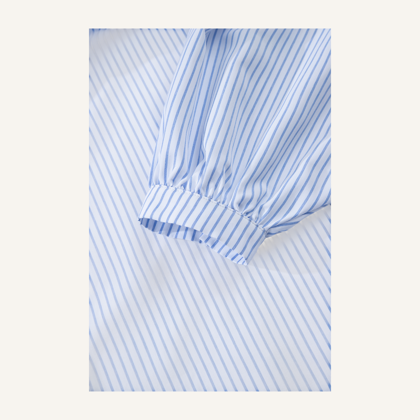 Sleeve view of a blue embroidered striped tunic shirt with long bell sleeves.