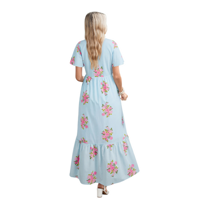 Rear view of a tiered light blue floral maxi dress showing the fluid drape of the skirt and flutter sleeve detail.