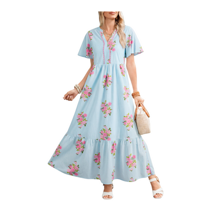 A woman wearing a light blue floral maxi dress with pink rose patterns, featuring flutter short sleeves and a notched neckline.